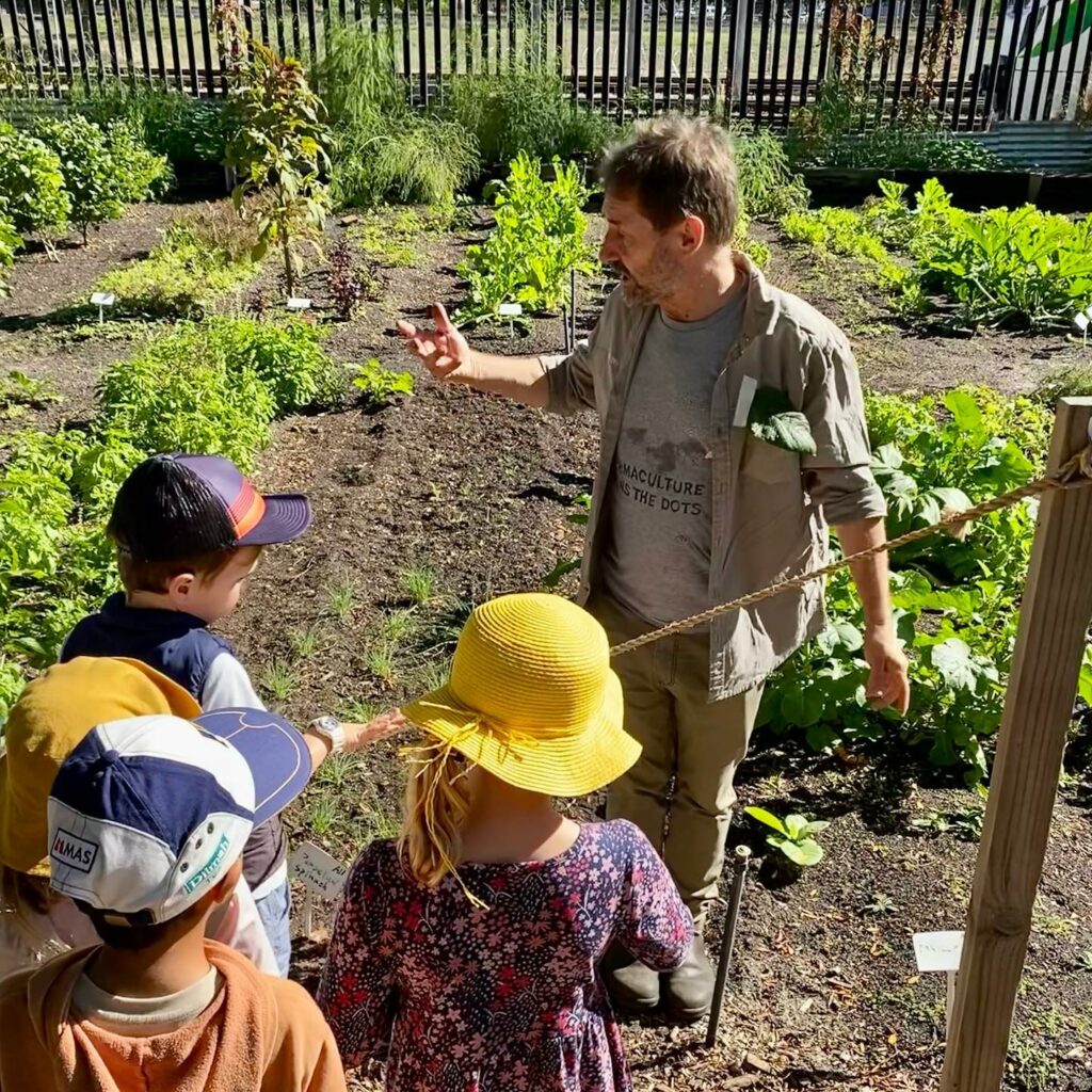 Farm team member Rod explains the market garden to a small group of children.