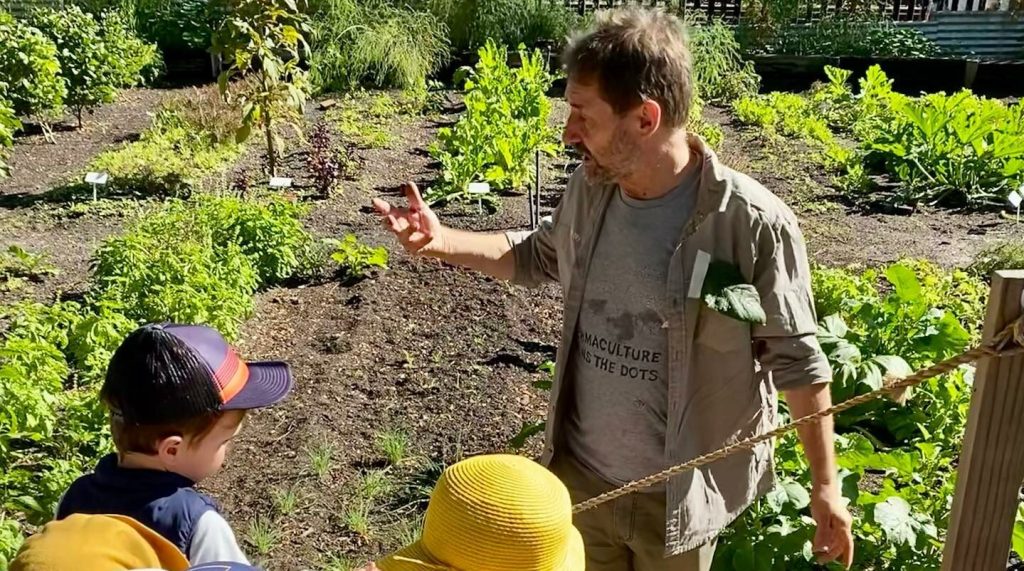 Farm team member Rod explains the market garden to a small group of children.